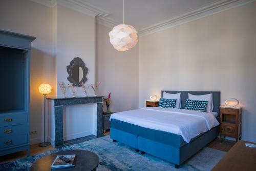 a bedroom with a blue bed and a fireplace at Garden of Eden in Antwerp