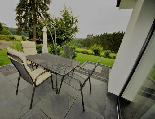 a glass table and chairs on a patio at Ruhe Oase mit tollem Fernblick inmitten der Natur in Limbach