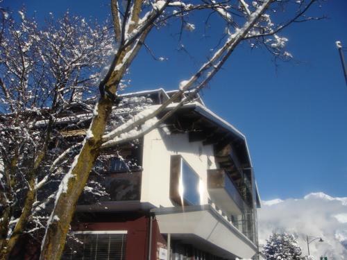 a building with snow on the branches of a tree at Alp Art Hotel Götzens in Innsbruck