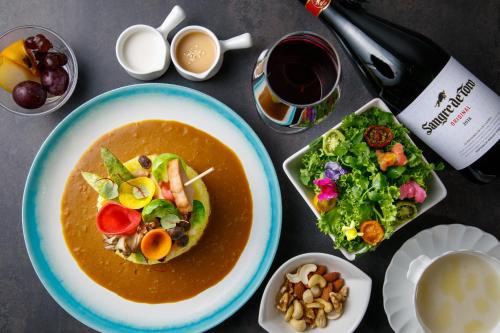 a table with a plate of soup and a salad and wine at Shin Osaka Esaka Tokyu REI Hotel in Suita