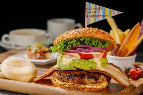 a large sandwich on a cutting board with french fries at Shin Osaka Esaka Tokyu REI Hotel in Suita