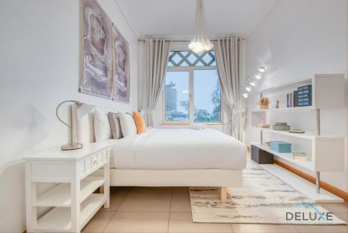 Lively 1 BR at Al Nabat Shoreline 8 Palm Jumeirah by Deluxe Holiday Homes في دبي: غرفة نوم بيضاء مع سرير أبيض ونافذة