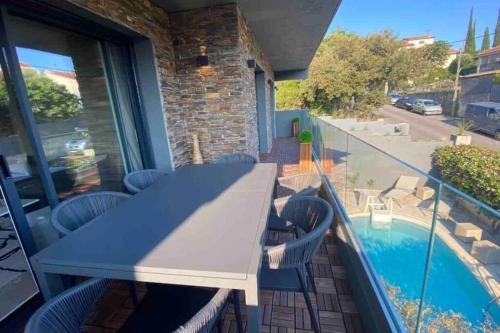 d'un balcon avec une table et des chaises, ainsi que d'une piscine. dans l'établissement Haut de villa de charme - 3 chambres 6pers, à Saint-Raphaël