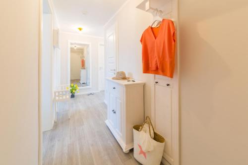 a bathroom with white walls and an orange shirt hanging on a wall at Whg 01 - Koje M in Zingst