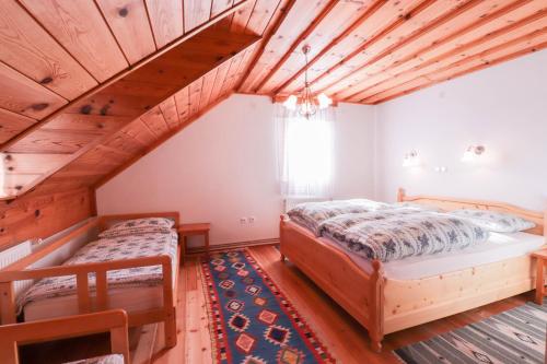 two beds in a room with wooden ceilings at House Alpine Rose in Mojstrana