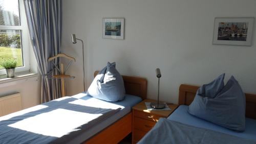a bedroom with two beds with blue pillows and a window at Wohnpark Sandkrug in Sandkrug