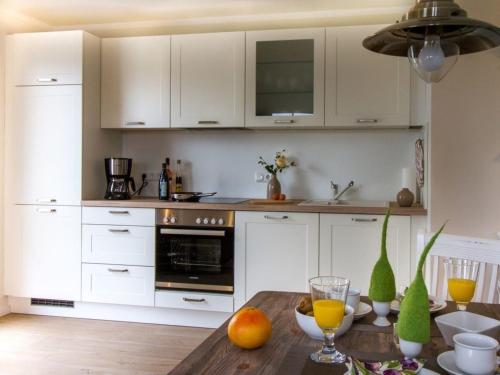 a kitchen with white cabinets and a wooden table at Whg 03 - Keekwind in Zingst