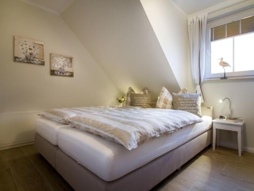 a white bed in a room with a window at Whg 03 - Keekwind in Zingst