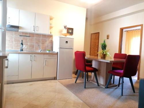 cocina y comedor con mesa y sillas rojas en Apartments Melinda, en Baška Voda