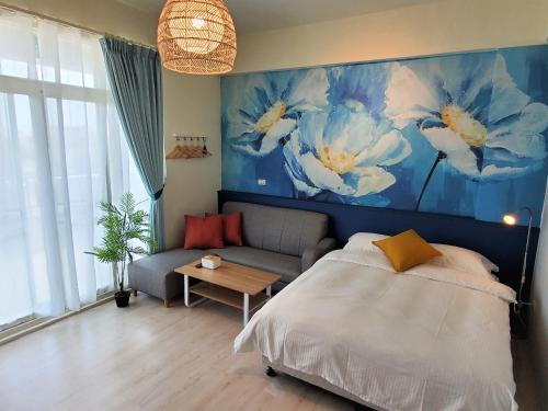 a bedroom with a bed and a couch and a painting at Touchai Life Guest House in Taitung City