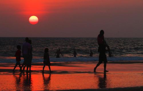 a group of people walking on the beach at sunset at Neela's Beach Inn in Hikkaduwa