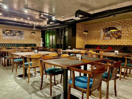 a restaurant with wooden tables and chairs and a brick wall at Alpha Plaza Hotel & SPA in Tashkent
