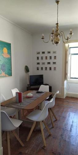 a dining room with a wooden table and white chairs at Casa da Carqueja 1 in Coimbra