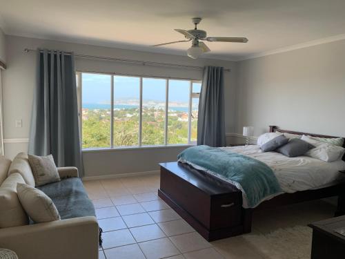 a bedroom with a bed and a couch and a window at 56 Robberg Road Plettenberg Bay in Plettenberg Bay