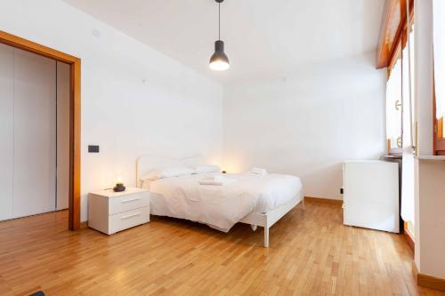 a bedroom with a white bed and a wooden floor at Attico Panoramico in Centro - Civetta in Belluno