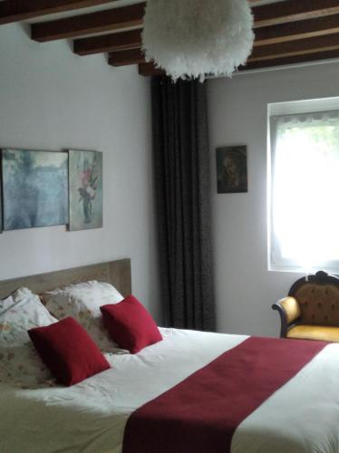une chambre avec un lit avec des oreillers rouges et blancs dans l'établissement La Solitaire, à Saint-Jean-aux-Bois