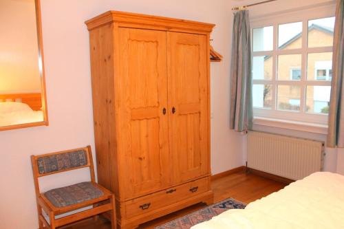 ein Schlafzimmer mit einem Holzschrank und einem Stuhl in der Unterkunft Finke-Ferienhaus - OG in Grömitz