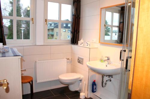 ein Bad mit einem WC, einem Waschbecken und Fenstern in der Unterkunft Finke-Ferienhaus - OG in Grömitz