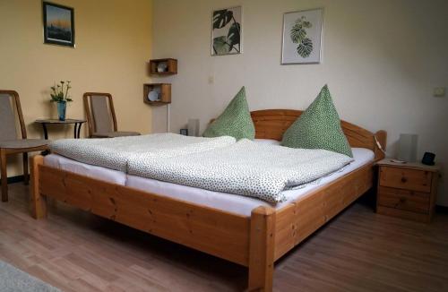 uma cama de madeira com almofadas verdes num quarto em Eifelferienhaus Thome em Lissendorf