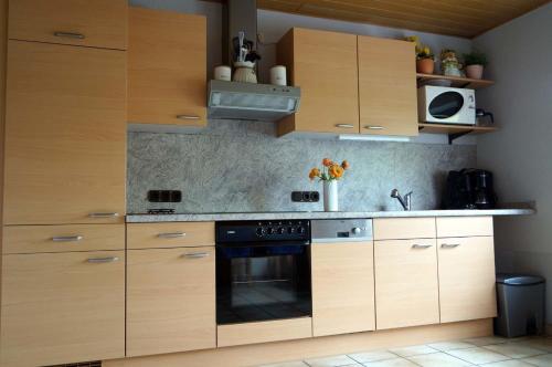 uma cozinha com armários de madeira e um forno com placa de fogão em Eifelferienhaus Thome em Lissendorf