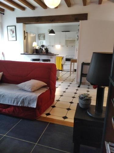 un salon avec un canapé rouge et une cuisine dans l'établissement La Solitaire, à Saint-Jean-aux-Bois