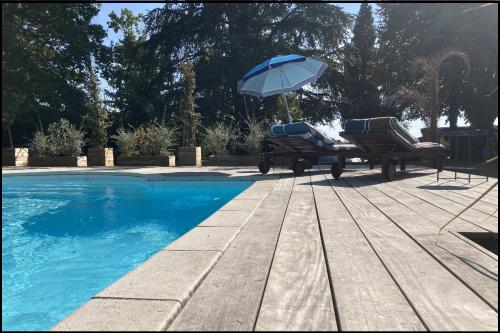 a swimming pool with two chairs and an umbrella at Domaine Cassevinha in Gauriac