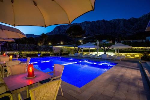 a pool with chairs and umbrellas and a table with a candle at Poseidon Mobile Home Resort in Makarska