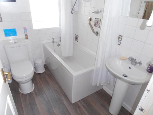a white bathroom with a toilet and a sink at Smithy Cottage in Blairgowrie
