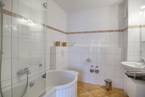 La salle de bains blanche est pourvue d'une baignoire et d'un lavabo. dans l'établissement Hausherr, Herbert FW 22, à Zingst