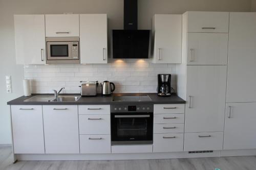 a white kitchen with a sink and a microwave at Meerblick Fehmarnsund 2 - direkt am Strand in Fehmarnsund
