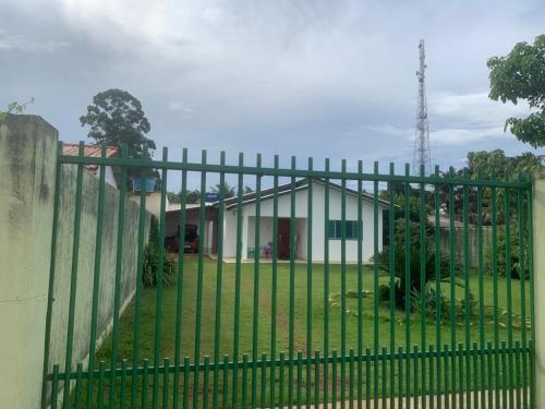 a green fence with a house behind it at Singela Casa em Chapada dos Guimarães in Chapada dos Guimarães