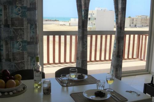 a table with a plate of food and wine on a balcony at Meeresrauschen auf Kreol in Sal Rei