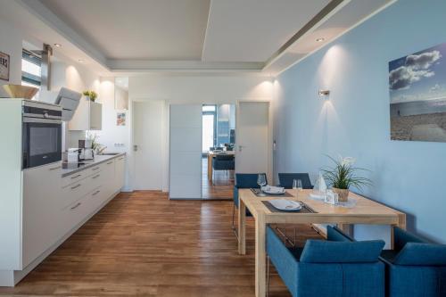 una cucina e una sala da pranzo con tavolo e sedie blu di Strandburg Azurblau a Burgtiefe auf Fehmarn 