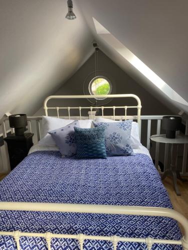 a bedroom with a bed with a blue comforter at Holly Cottage The Studio in Hinstock
