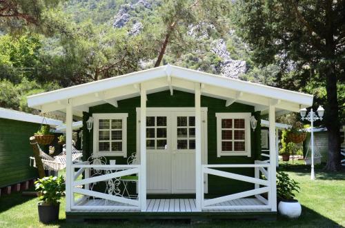 a green cottage with a white roof and a porch at Lukkies Lodge Cirali in Cıralı
