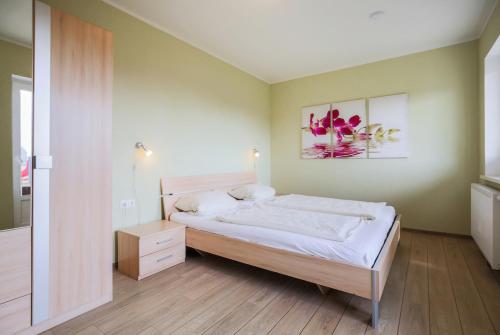SahrensdorfにあるFerienhof Büdlfarm - Hühnerstallのベッドルーム1室(ベッド1台付)が備わります。壁には絵画が飾られています。