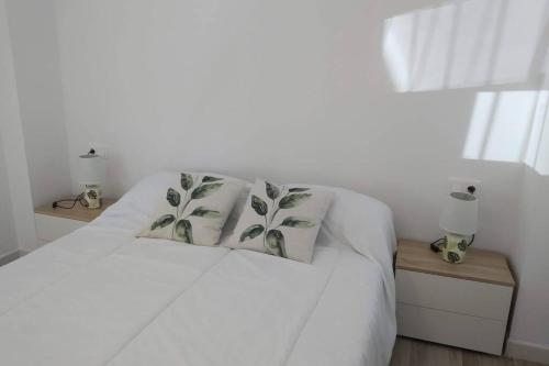 uma cama branca com duas almofadas em cima em Precioso apartamento en San Juan de Alicante em San Juan de Alicante