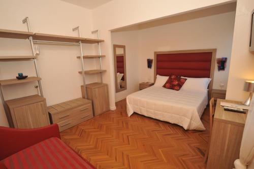 a bedroom with a bed with a red headboard at Hotel Astoria in Fermo
