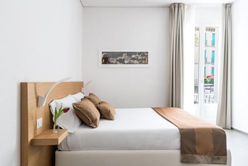 a white bedroom with a bed and a window at Aurà - Guest House Iblea in Ragusa