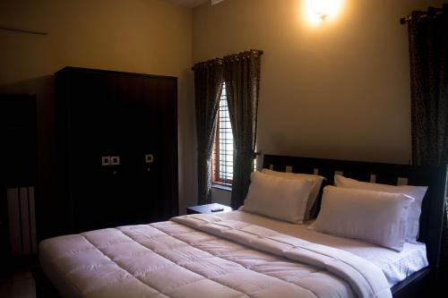 ein Schlafzimmer mit einem großen Bett mit weißer Bettwäsche und einem Fenster in der Unterkunft Maliyakal Homestay in Ernakulam