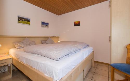 ein Schlafzimmer mit einem weißen Bett mit einem Holzrahmen in der Unterkunft Dorfkoje in Sankt Peter-Ording