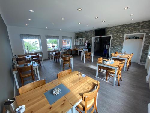 Un comedor con mesas y sillas de madera. en Die Schlafstube, en Neuharlingersiel