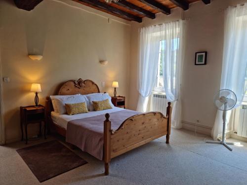 a bedroom with a large bed and two windows at Domaine de Pouroutounat in Mirepoix