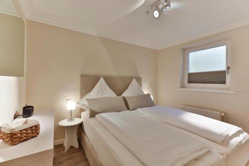 ein weißes Schlafzimmer mit einem großen Bett und einem Fenster in der Unterkunft Pebbles in Westerland