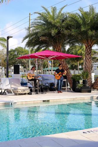 two people playing guitars next to a swimming pool at The Saint Hotel in St Pete Beach