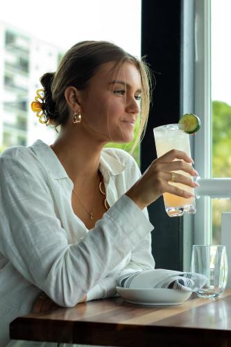 a woman sitting at a table with a glass of beer at The Saint Hotel in St Pete Beach