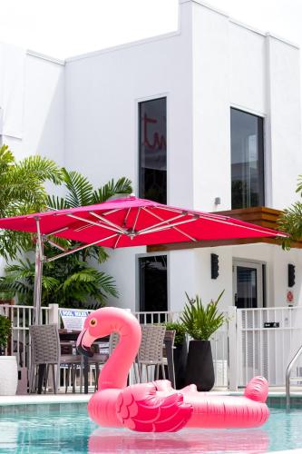 a pink flamingo float in a pool with an umbrella at The Saint Hotel in St Pete Beach