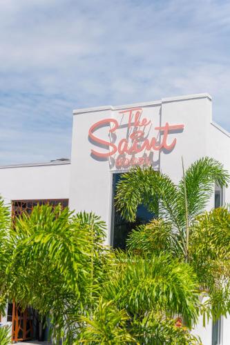 a sign for the hotel behind some palm trees at The Saint Hotel in St Pete Beach