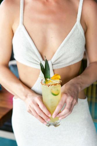 a woman in a white dress holding a drink at The Saint Hotel in St Pete Beach