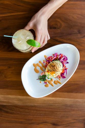 a person holding a drink next to a plate of food at The Saint Hotel in St Pete Beach